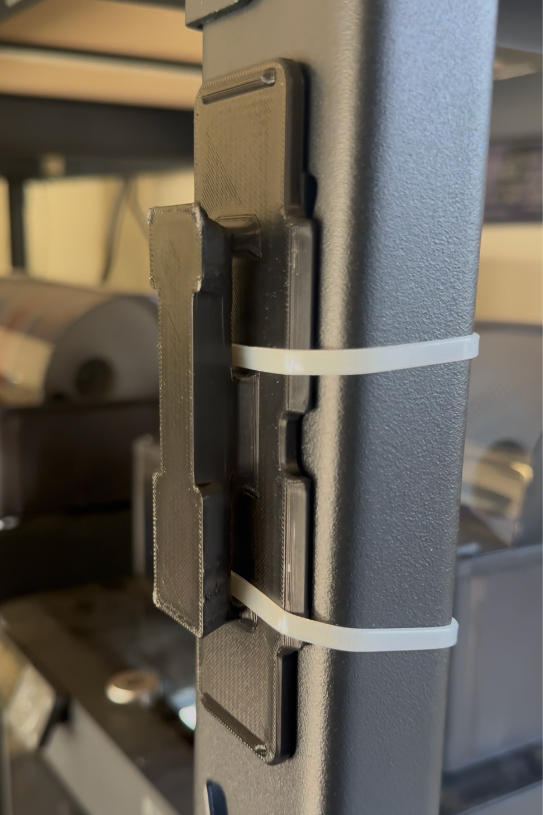Close-up of a black metal hinge with a white band on a blurred background